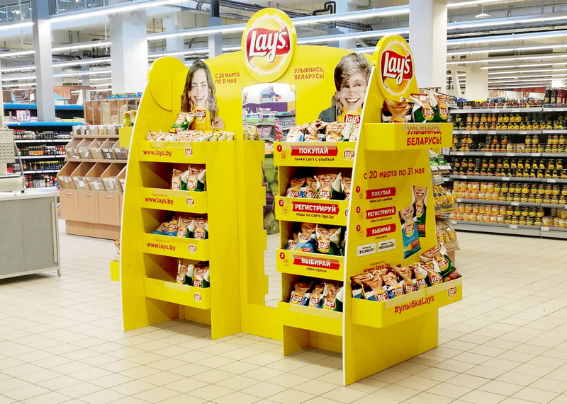 A yellow Lay's chips promotional display stand in a grocery store.